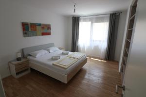 a white bedroom with a bed and a window at Apartment Sandrita in Kotor