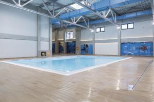 a large swimming pool in a room with a wooden floor at Apartman Luxor in Jagodina