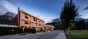 a building on a street with mountains in the background at Hotel Arnica Scuol - Adults Only in Scuol