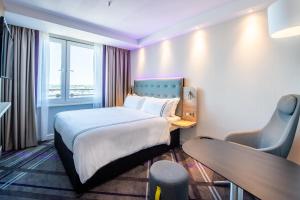 a hotel room with a bed and a desk and a window at Premier Inn Köln City Süd in Cologne