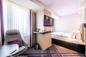 a hotel room with a bed and a chair and a tv at Premier Inn Köln City Süd in Cologne
