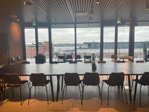una gran mesa y sillas en una habitación con una gran ventana en UNITY Tampere Trikootehdas en Tampere