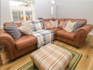 a living room with a brown couch and a ottoman at Sunshine Cottage Tideswell, Games room included. in Tideswell