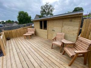 a wooden deck with two chairs and a cabin at Sunshine Cottage Tideswell, Games room included. in Tideswell