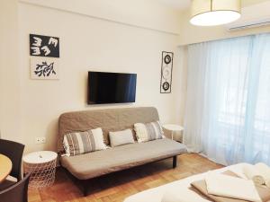 a living room with a couch and a flat screen tv at Acropolis Oasis by YHA in Athens