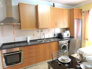 a kitchen with wooden cabinets and a sink at Casa Izamar in Monte Gordo