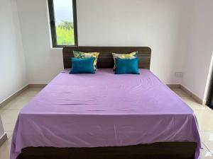 Una cama morada con almohadas azules en una habitación. en Green Village Duplex, en Grand Gaube