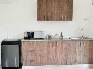 Una cocina con armarios de madera, fregadero y microondas. en Green Village Duplex, en Grand Gaube