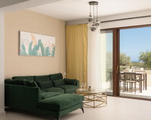 sala de estar con sofá verde y mesa de cristal en Mela Luxury Apartments, en Maroulás