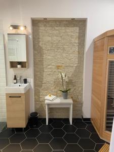 ein Badezimmer mit einem weißen Waschbecken und einer Steinmauer in der Unterkunft Au cocon de Bélice in Benon