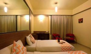 a hotel room with two beds and a mirror at FabHotel Prime Ivy Studio in Pune