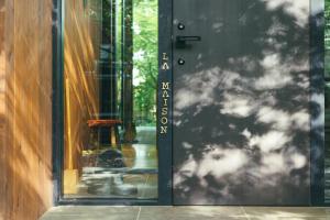une porte d'immeuble avec une pancarte dessus dans l'établissement La Maison Karuizawa, à Karuizawa