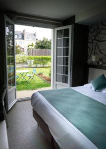 1 dormitorio con 1 cama y puerta corredera de cristal en Quality Hotel La Marebaudière Vannes Centre, en Vannes