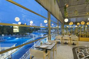 a restaurant with tables and chairs and a pool at Titanic Deluxe Lara in Lara