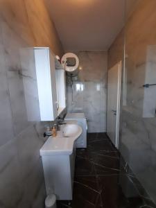 a bathroom with a white sink and a shower at Arlis House in Golem +23 photos
