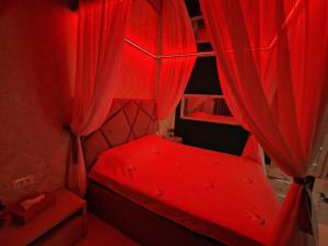 uma cama vermelha com cortinas vermelhas num quarto em XMX Jacuzzi and Baldachin Studio em Bucareste