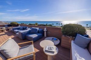 eine Terrasse mit blauen Sofas und Tischen und Meerblick in der Unterkunft Hotel Calatrava in Palma de Mallorca
