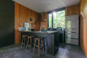 a kitchen with a island with bar stools and a refrigerator at La Maison Karuizawa in Karuizawa +38 photos