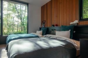 2 camas en un dormitorio con ventana en La Maison Karuizawa, en Karuizawa