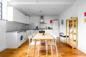 eine Küche mit einem Holztisch und weißen Geräten in der Unterkunft Trendy East London Flat SH11 in London