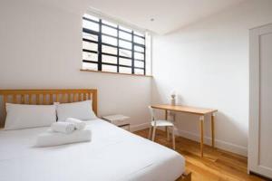 1 dormitorio con cama, escritorio y ventana en Trendy East London Flat SH11 en Londres