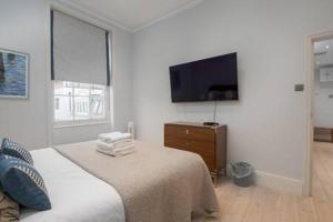 een slaapkamer met een bed en een flatscreen-tv bij Trendy Hampstead Flat RH7 in Londen