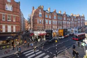 a busy city street with buildings and pedestrians and a red bus at Trendy Hampstead Flat RH7 in London