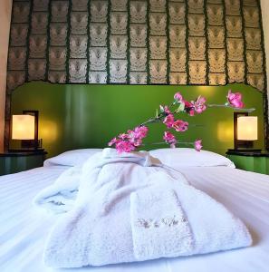 ein Bett mit einer weißen Decke und rosa Blumen drauf in der Unterkunft Hotel Verdi Boutique Hotel in Parma