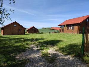 a dirt road in a field next to two barns at Domki na zaciszu w Rynie in Ryn