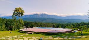 a pool in a field with a mountain in the background at Coffeeberry Hills Chikamagalur in Chikmagalūr
