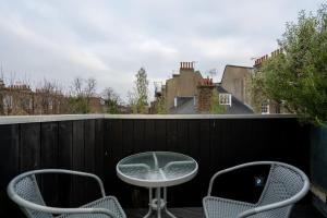 um pátio com 2 cadeiras e uma mesa na varanda em Award Winning 2 Bedroom House, King's Cross em Londres