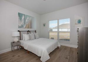 a white bedroom with a bed and a window at Sweet Escapes House in Foley