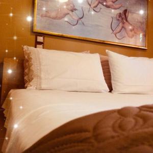 uma cama com almofadas brancas e um quadro na parede em The Little Blooming House em Agíasma