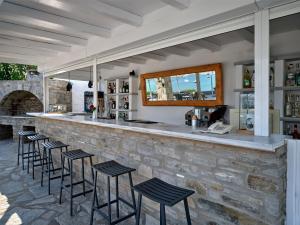 a stone bar with black stools in front of it at Parian Village Beach Hotel - Adults Only in Parikia