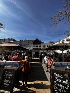 un grupo de personas caminando por un mercado con señales en George & Dragon, en Dartmouth