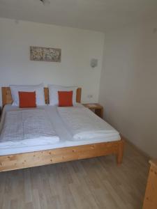 Schlafzimmer mit einem Bett mit weißer Bettwäsche und orangefarbenen Kissen in der Unterkunft Appartementhaus Linter in Dorf Tirol