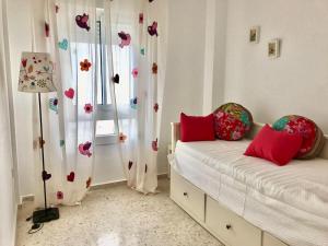 1 dormitorio con 2 camas con almohadas rojas y ventana en APARTAMENTO VISTAS AL MAR - Valdelagrana Playa, en El Puerto de Santa María