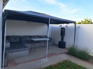 a patio with a couch and a table under a tent at Apartament un dormitor și living la curte Corbu in Corbu