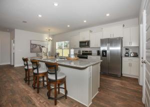 a kitchen with white cabinets and a kitchen island with bar stools at Luxury Getaway House in Foley