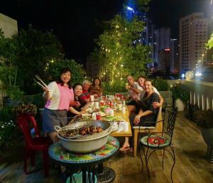 un grupo de personas sentadas alrededor de una mesa comiendo comida en La Casa Hotel Nha Trang, en Nha Trang