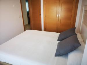 1 dormitorio con 1 cama blanca y 2 almohadas azules en Camposoto, en San Fernando