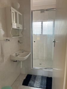 a white bathroom with a sink and a shower at Dolphin View Self Catering in Scottburgh