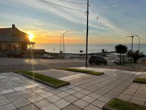 ein Sonnenuntergang über dem Meer mit Autos auf einem Parkplatz in der Unterkunft Lujo Junto al Mar - Cochera y Terraza Privada in Mar del Plata