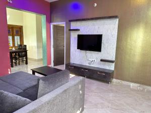uma sala de estar com um sofá e uma televisão de ecrã plano em Anthara service apartments em Belūr