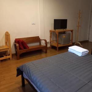 a bedroom with a bed and a tv and a chair at Happy Hostel in Bangkok