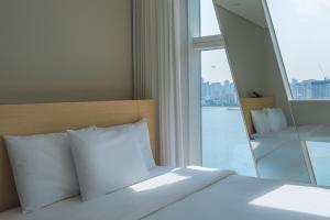 a bed with white pillows in a room with a window at Hotel Marine view in Busan