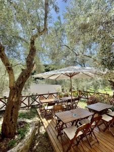 una terraza de madera con mesas, sillas y sombrilla en Apartments Eman Resort, en Ulcinj