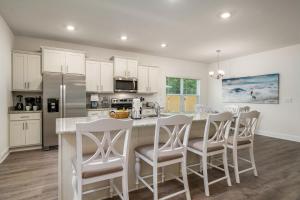 a kitchen with white cabinets and a island with bar stools at Carly Place House 1893 in Foley