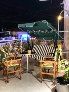 a patio with a table and chairs and a green umbrella at Casagrande Studio in Kriopigi