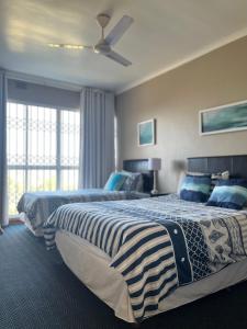 a bedroom with two beds and a ceiling fan at Dolphin View Self Catering in Scottburgh